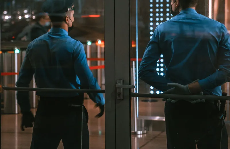 Uniformed security guards standing at a building entrance